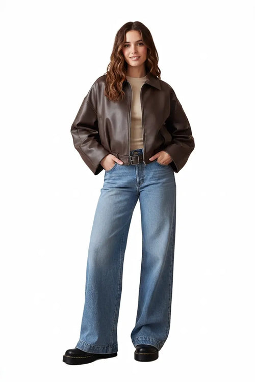 Woman wearing a brown leather jacket and blue jeans on a white background